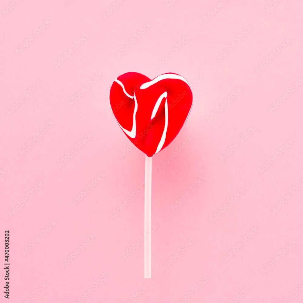 Red lollipop heart on a white stick over pink background. Top view, copy space