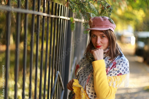 woman in a cap near a metal fence in a park