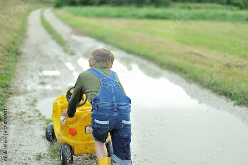 A little boy is playing with  toy cars in a huge puddle.
 photo