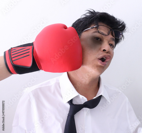Business competition concept, businessman knocked out by getting punched in his face with red boxing gloves on white background. © sittinan