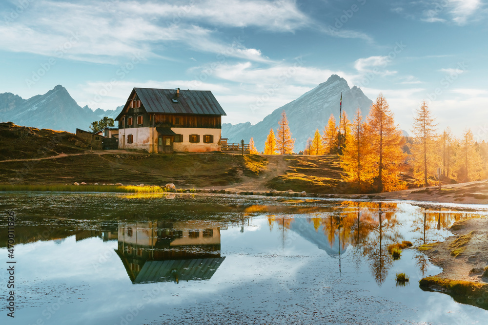 Fototapeta premium Rifugio Croda on Federa Lake in sunrise time. Autumn mountains landscape with Lago di Federa and bright orange larches in the Dolomite Apls, Cortina D'Ampezzo, South Tyrol, Dolomites, Italy
