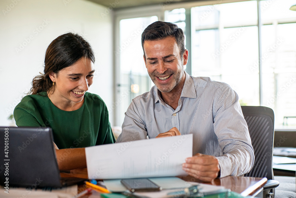 Smiling young woman and mature man working in office Smiling young woman and mature man working in office