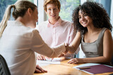 Young couple shaking hands with businesswoman during meeting