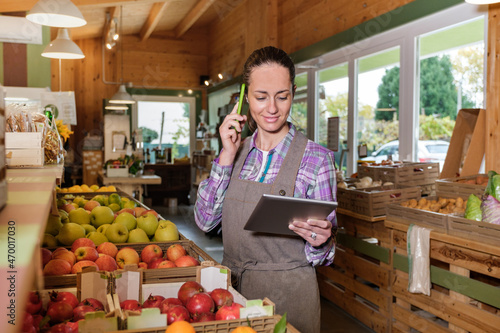 Fotografija Portrait of happy female sales assistant in a grocery using digital tablet and t