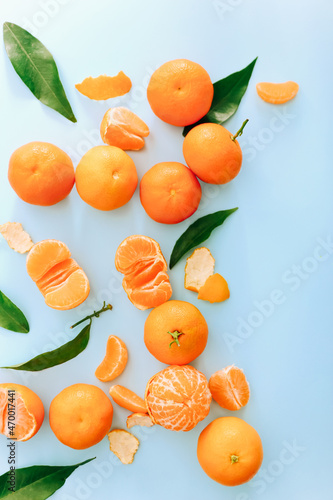 Fresh clementines with leaves on blue background, top view