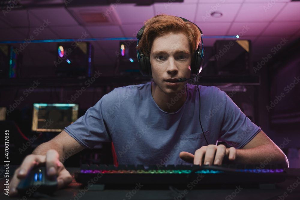 Man wearing headset sitting in front of the computer and being involved at the game Man wearing headset sitting in front of the computer and being involved at the game