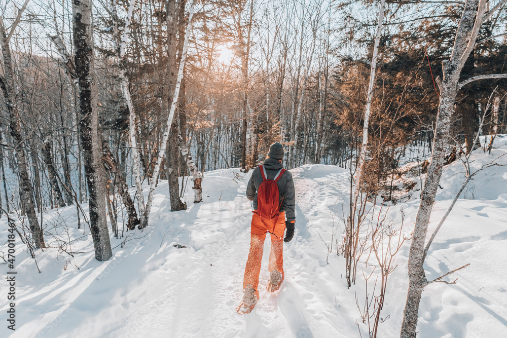 © Maridav - Snowshoeing people in winter forest with snow covered trees on snowy day. Man on hike in snow hiking in snowshoes living healthy active outdoor lifestyle