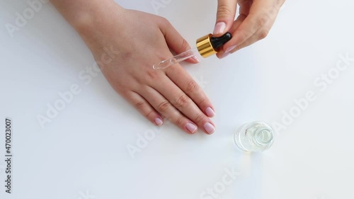 Hand of woman with pipette drop of serum or hyaluronic acid on white background. Hands of a beautiful woman dripping serum collagen.