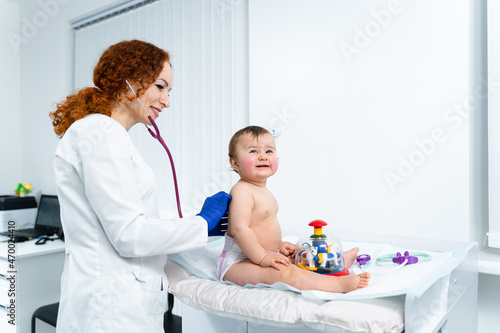 Pediatrician providing healthcare for her baby patient in the office of clinic for children. Neonatologist. Medical appointment little child one year old in the clinic. Health care of children, kid