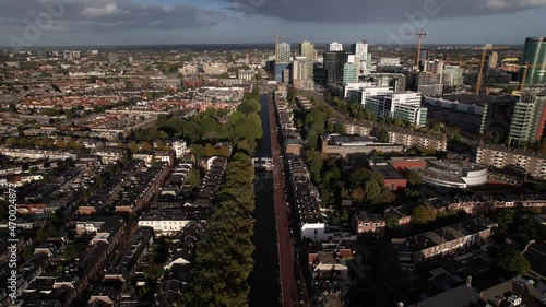 Canal between Lombok and Dichterswijk neighbourhoods in Utrecht, The Netherlands, with old fashioned windmill in the foreground and contemporary high rise construction of financial district behind photo