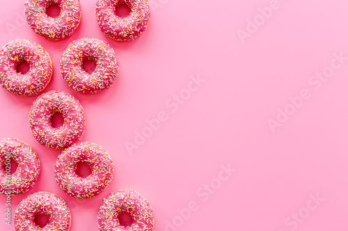 Pink donuts with icing and sprinkles, top view. Sweet snacks set