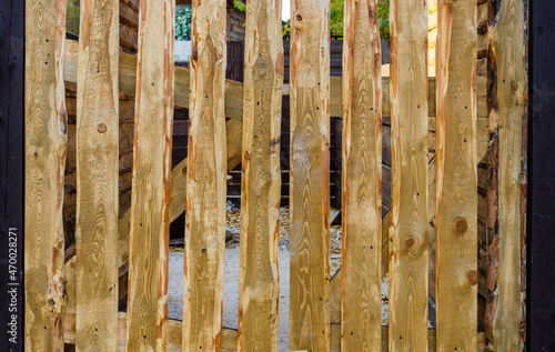A fragment of a wooden fence made of untreated wooden boards.