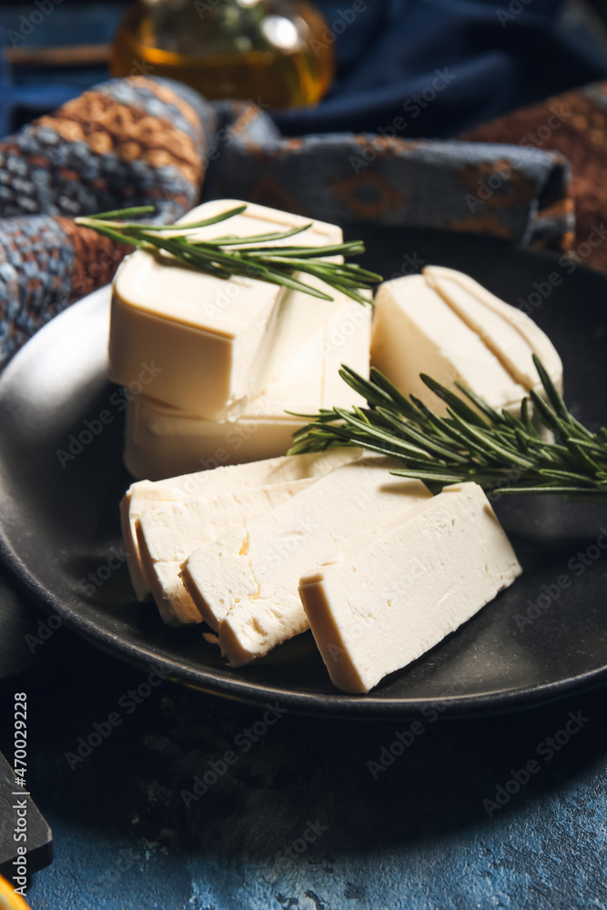 Plate with delicious feta cheese with rosemary on color background