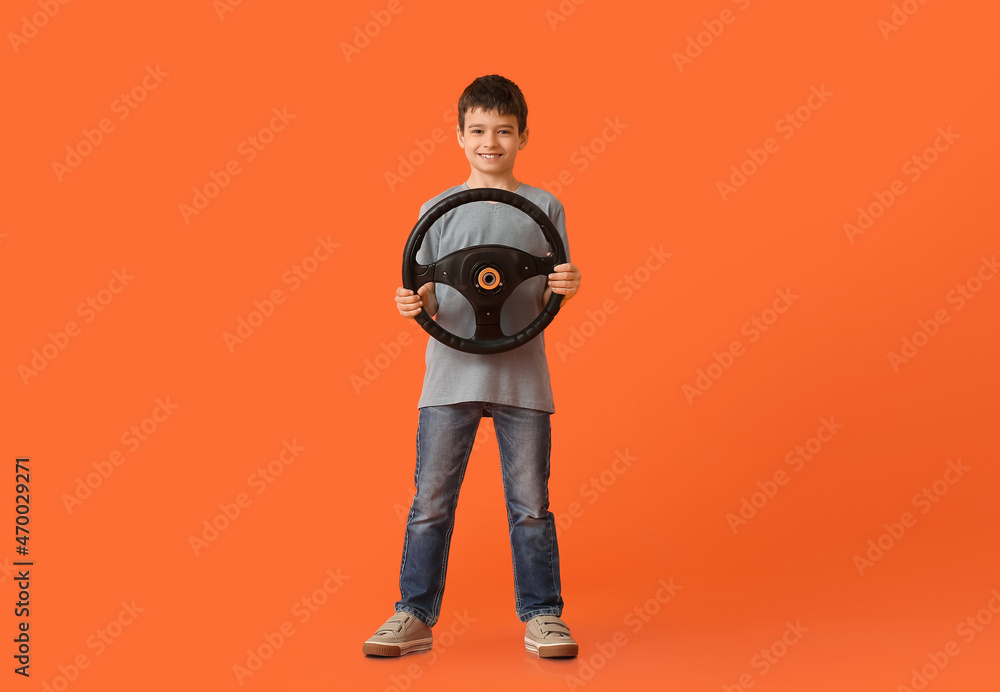 Fototapeta premium Little boy with steering wheel on color background