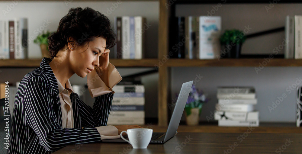 Focused businesswoman working on laptop in workspace Focused businesswoman working on laptop in workspace
