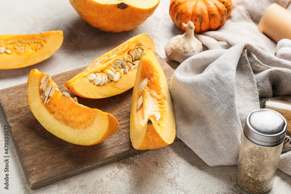 Wooden board with fresh pumpkin pieces on light background Wooden board with fresh pumpkin pieces on light background