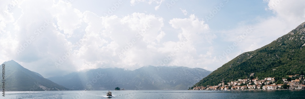 Motor boat sails past the coast of Perast. Montenegro. Panorama