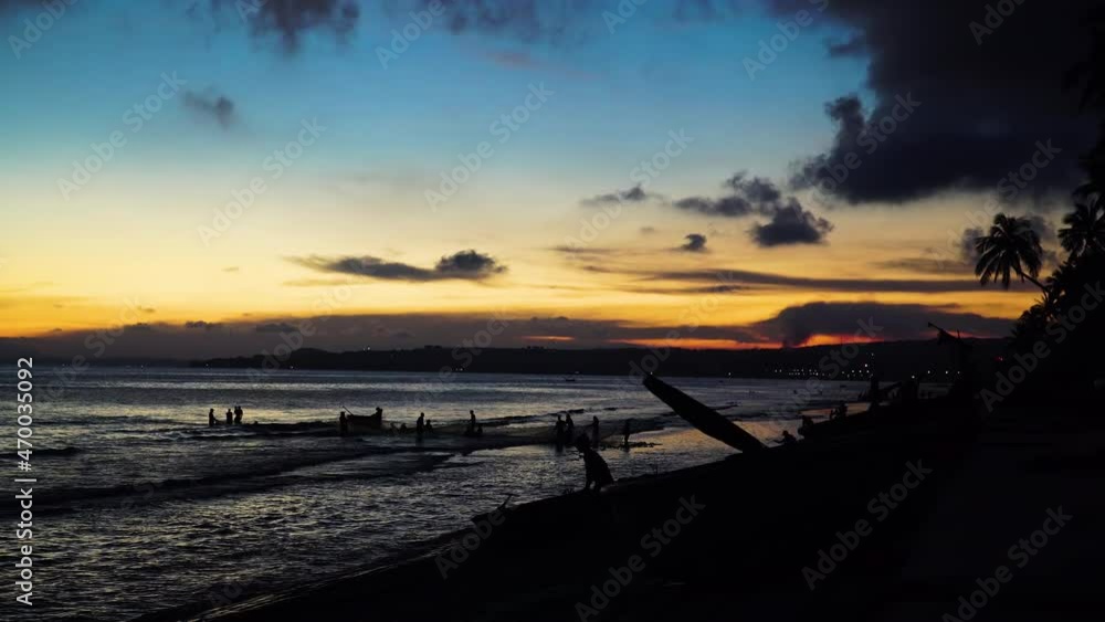 Silhouette, men pulling out fishing net from ocean beach during sunset. Vietnam