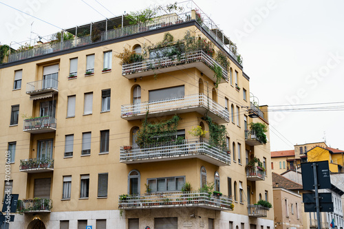 House facade with flower pots on balconies. Milan, Italy © Nadtochiy