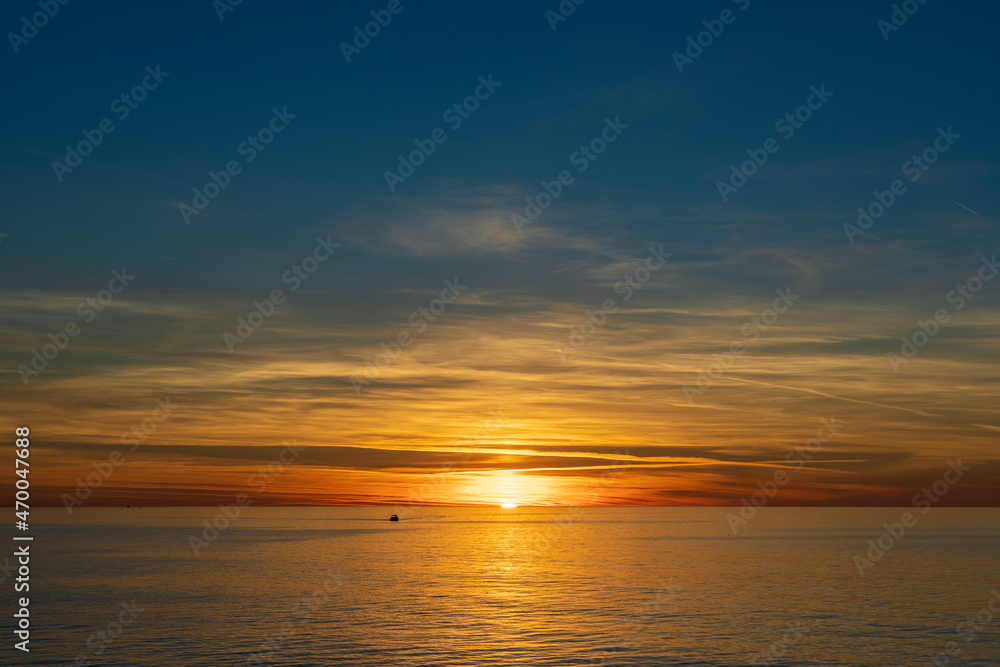Majestic view of a setting down sunset sun with a sea water surface