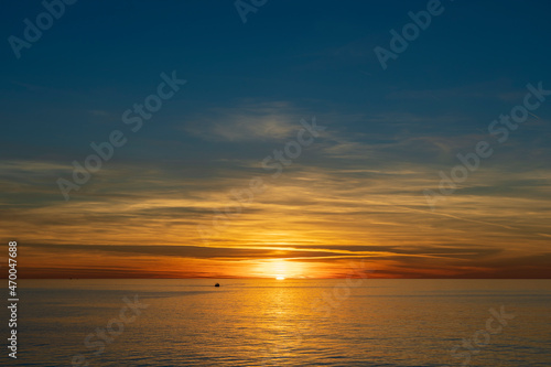 Majestic view of a setting down sunset sun with a sea water surface © OlegD
