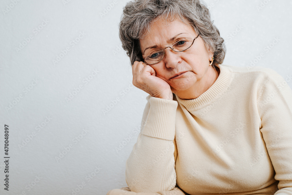Portrait of senior sad woman in depressive mood sitting alone at home and looking down. Lonely elderly unhappy caucasian woman, close-up. Loneliness, mental health, problems, fatigue concept Portrait of senior sad woman in depressive mood sitting alone at home and looking down. Lonely elderly unhappy caucasian woman, close-up. Loneliness, mental health, problems, fatigue concept