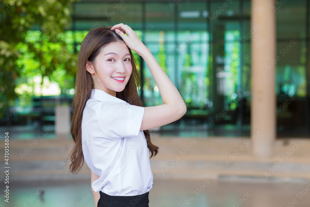 Fototapeta premium Portrait of an adult Thai student in university student uniform. Asian beautiful girl standing smiling happily looking at camera in university