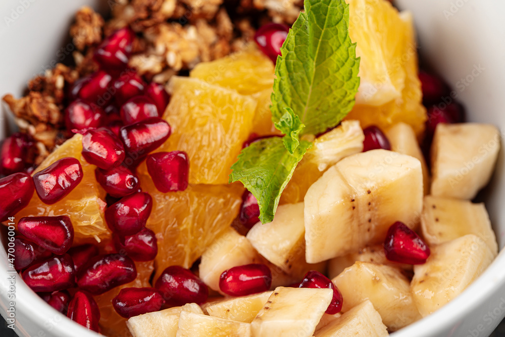 Closeup on sweet granola breakfast with banana pommegranate and oranges Closeup on sweet granola breakfast with banana pommegranate and oranges