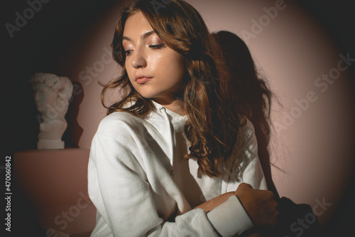 Young pretty woman in white sweater with curly hair opposite the lantern, on the pink background photo