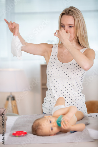 mother changing smelly baby diaper