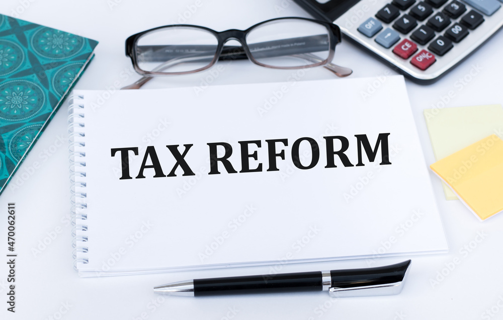 Notepad with text TAX REFORM with pen, office tools on the desktop. Notepad with text TAX REFORM with pen, office tools on the desktop.