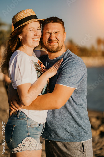  bright sun. a man and a woman in love squinting from the sun hug on the beach.