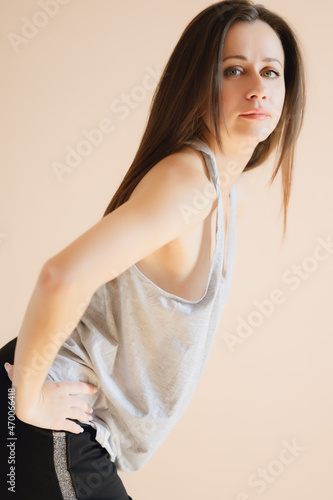 Graceful young woman posing against beige wall.