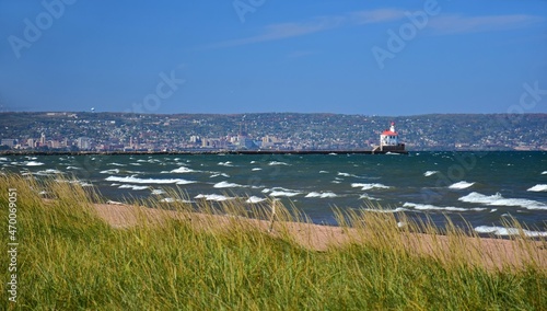 sea grass, waves,  sand, duluth,  and the wisconsin point lighthouse as seen from wisconsin point across lake superior on a sunny fall day in wisconsin