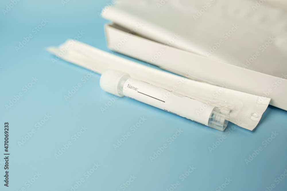 Rapid antigen COVID-19 self test kit on blue background. The UK day 2 rapid lateral flow swab test for fully vaccinated arrivals. Selective focus. Rapid antigen COVID-19 self test kit on blue background. The UK day 2 rapid lateral flow swab test for fully vaccinated arrivals. Selective focus.