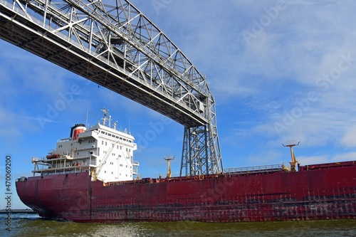  a saltie freighter from quebec passes under the aerial lift bridge from lake superior into duluth harbor on a sunny fall day in duluth, minnesota 