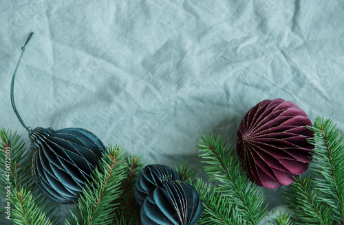 Spruce twigs with paper decorations on the green linen crumpled textile background