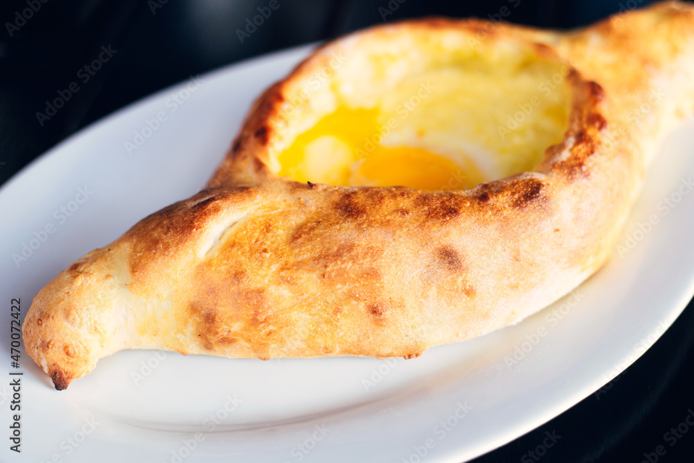Khachapuri on a white plate - a traditional Caucasian dough recipe with a raw egg