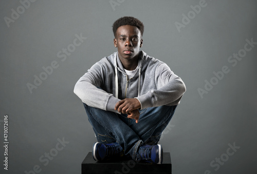 Young Black man posing cross-legged in a studio
