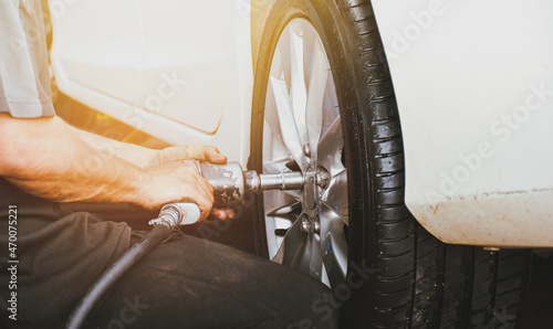 The mechanics remove the car wheel with an air impact wrench in the auto repair shop service