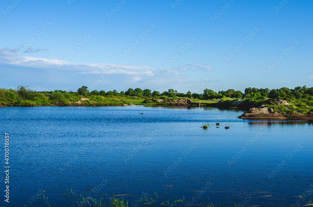 Blue water in a quarry pond under a blue sky. Flooded quarry