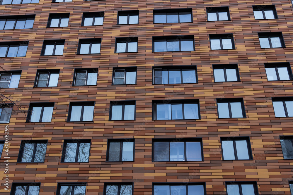 Wall of a trendy modern building with windows with an abstract brown rectangular tile facade. City landscape. Close-up Wall of a trendy modern building with windows with an abstract brown rectangular tile facade. City landscape. Close-up