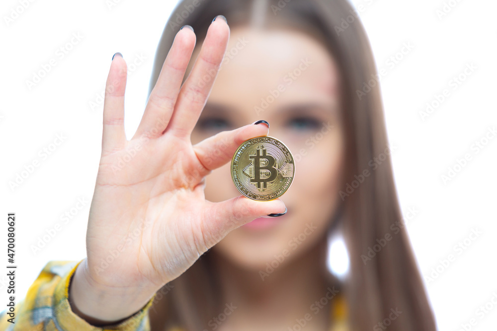 Close up shot of a physical bitcoin cryptocurrency held in front of a face in a hand of a beautiful woman. Concept of financial well being, growth, investment Close up shot of a physical bitcoin cryptocurrency held in front of a face in a hand of a beautiful woman. Concept of financial well being, growth, investment