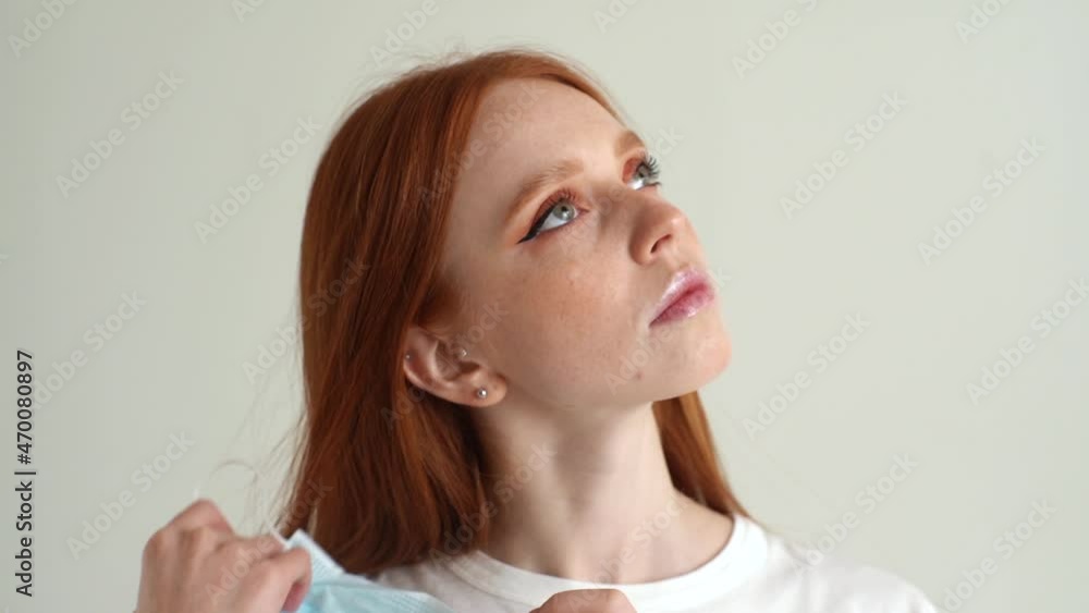 Close-up face of unhappy young woman with skin acne or pimples from wearing face mask touching swollen, spot, maskne, scar, skin allergy on chin, on white isolated background in studio, slow motion. Close-up face of unhappy young woman with skin acne or pimples from wearing face mask touching swollen, spot, maskne, scar, skin allergy on chin, on white isolated background in studio, slow motion.