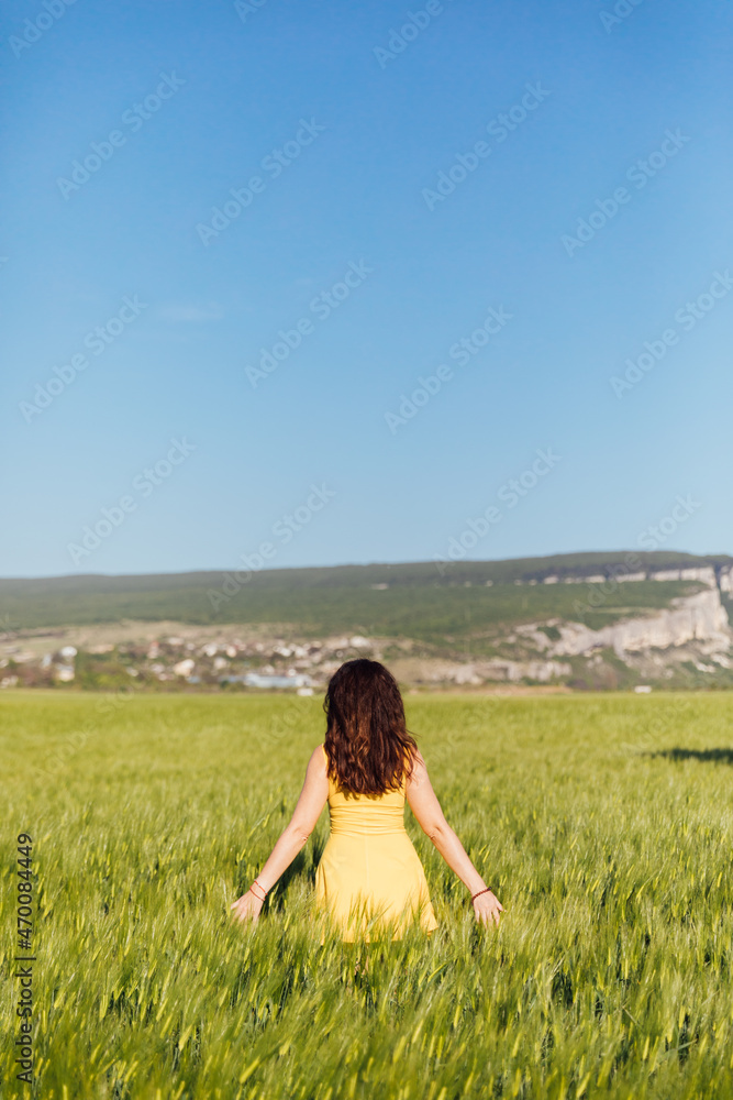 beautiful brunette woman in a field of green wheat