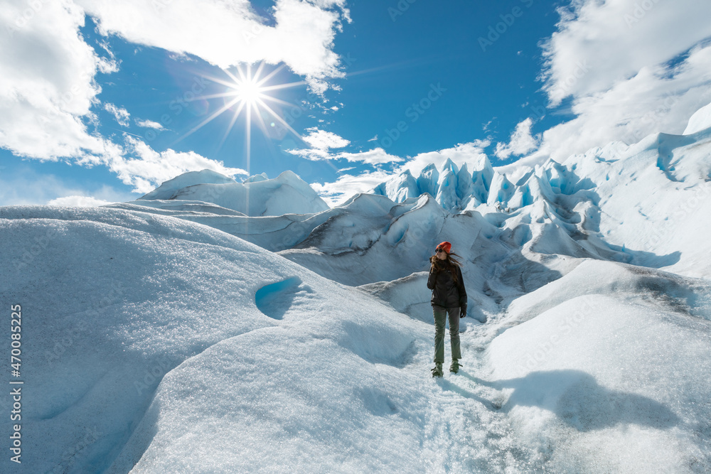 A woman stands on the ice formation of the Perito Moreno Glacier and smiling