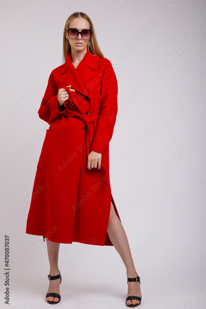 High fashion photo of a beautiful elegant young woman in a pretty red autumn coat, stylish sunglasses posing on white background. Studio Shot. Slim figure. High fashion photo of a beautiful elegant young woman in a pretty red autumn coat, stylish sunglasses posing on white background. Studio Shot. Slim figure.