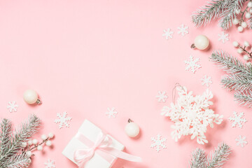 Christmas decorations at pink background. Fir tree, present box and white christmas decorations. Top view with copy space.