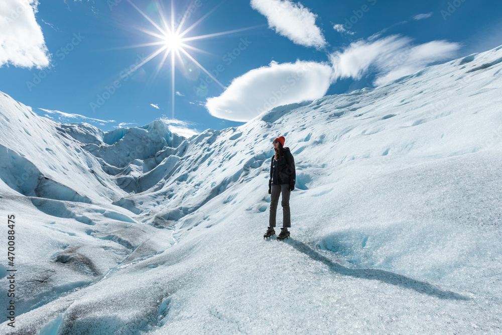 A woman standing on the ice formation of the Perito Moreno Glacier and looking up left