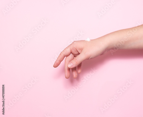 Women's hands with skin moisturizer on a pink background. Self-care, cosmetology.